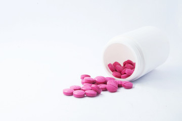 Pink medicine tablet antibiotic pills spilling out of a bottle