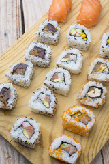 Different Sushi rolls,wasabi and ginger on a plate on wooden bac