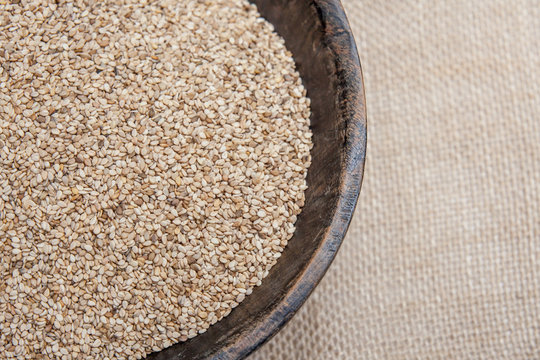 Sesame seeds in rustic wooden bowl on sackcloth