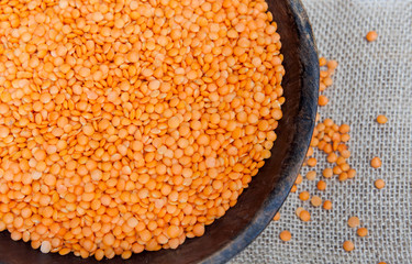 Red lentils in rustic wooden bowl on sackcloth