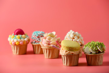 Tasty cupcakes with original decoration on pink background