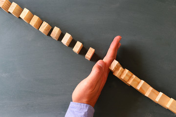 a male hand stopping the domino effect