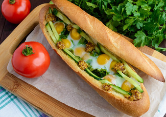 Baked crispy baguette with fried eggs, cucumbers and greens