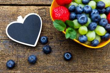 fresh organic fruits on wooden table, black heart