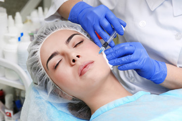 Young woman receiving plastic surgery injection on her face, closeup