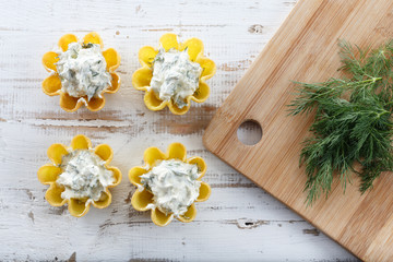 Tartlets filled with cheese and dill salad against rustic wooden background