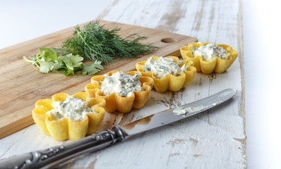 Tartlets filled with cheese and dill salad against rustic wooden background