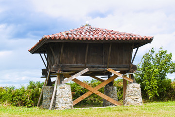 Hórreo asturiano sobre cuatro pilares de piedra bajo el cielo azul