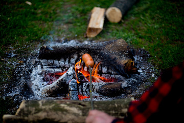 Man drinking coffee by the fire at a campsite on the river bank.