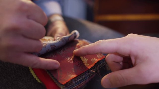  Client in a meeting with tailor, looking at fabrics for custom made suit
