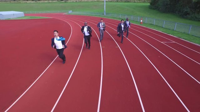  Drone footage of competitive businessmen racing each other at running track