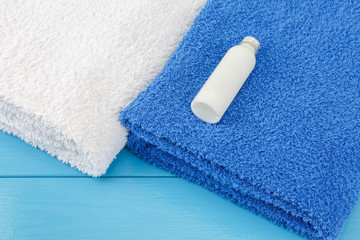 Towels with little bottle of shampoo on a blue wooden background