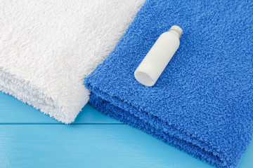 Towels with little bottle of shampoo on a blue wooden background