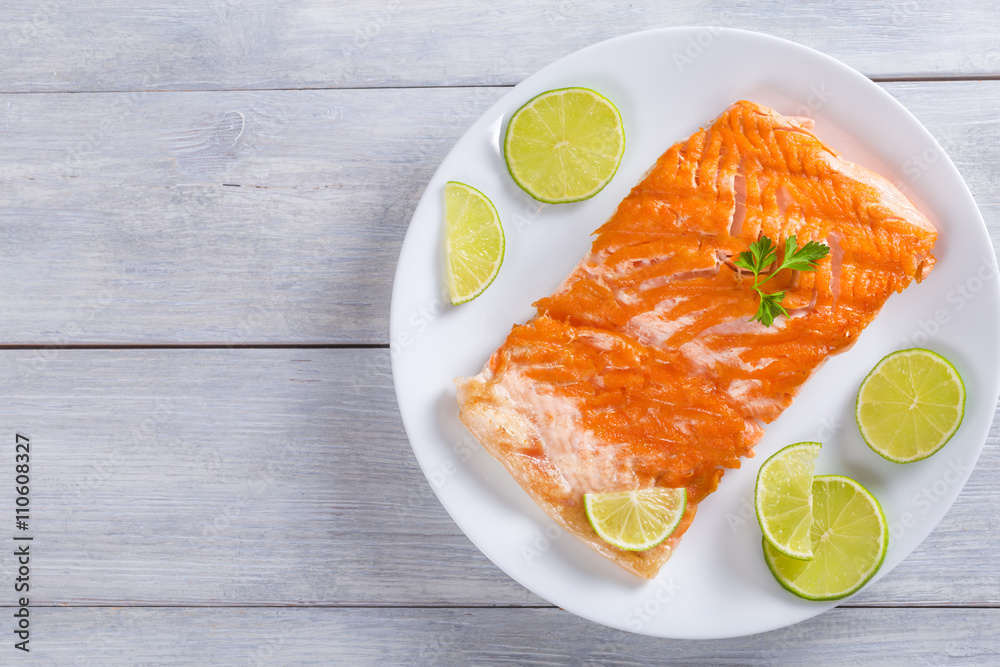 Poster salmon fillet on a white dish, top view