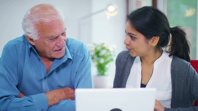  Cheerful home support worker showing elderly man how to use a computer