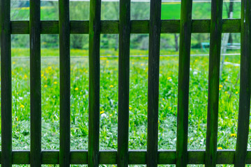 Detail of railing with grass field behind it. Old wooden railing protecting garden