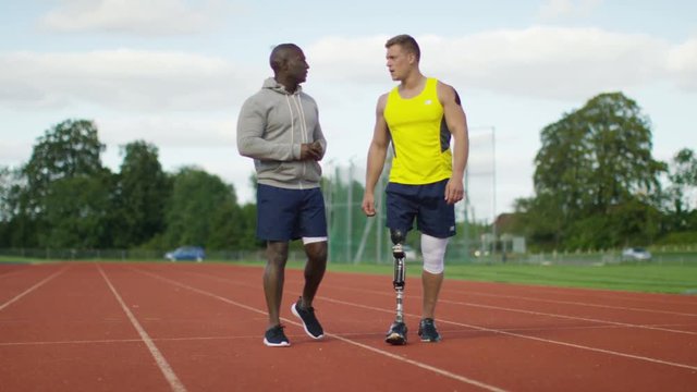  Disabled athlete with prosthetic leg working out with trainer @ running track