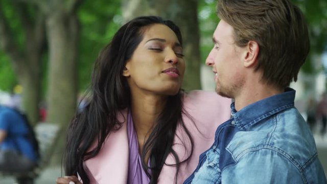  Attractive mixed ethnicity couple in the park share a kiss.