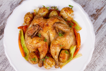 Roasted chicken with potato, carrot, leek and thyme.View from above, top studio shot