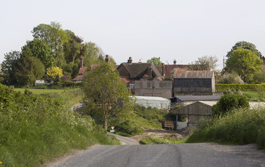 Typical English Farm. A country road curves and dips past a typical old country farmstead with its out buildings and barns.