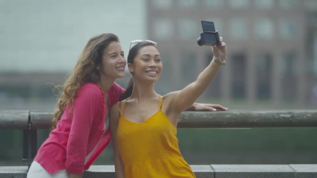  Happy attractive female friends posing for selfie outdoors in the city