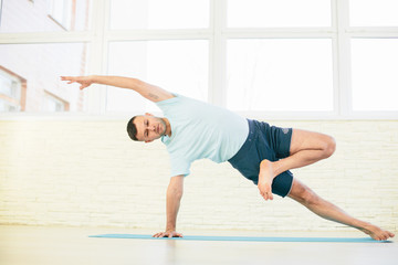 Naklejka premium Handsome yoga man practice in a training hall background. Yoga concept.