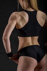 Young muscular woman posing on black
