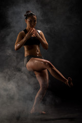Fototapeta na wymiar Young muscular woman posing on black