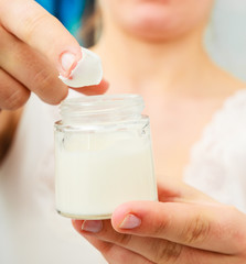 Woman applying skin cream on face