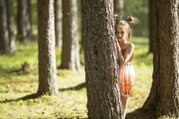 Ten-year-old girl looks out from behind a tree.