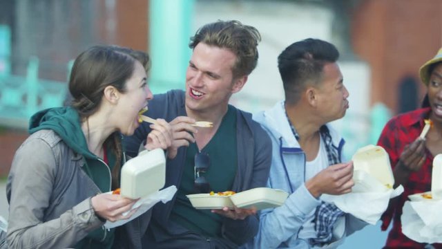  Happy mixed ethnicity group of friends eating fried chips in urban area