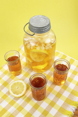 Three fruit glasses with iced tea in front of a vintage mason jar - yellow background, yellow checkered tablecloth