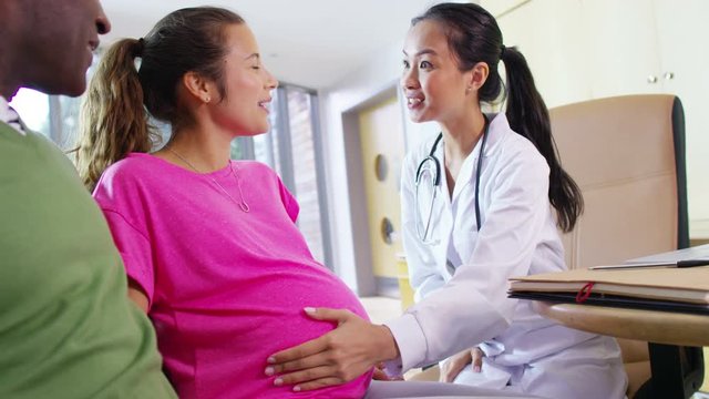  Friendly doctor talking to couple who are expecting a baby 