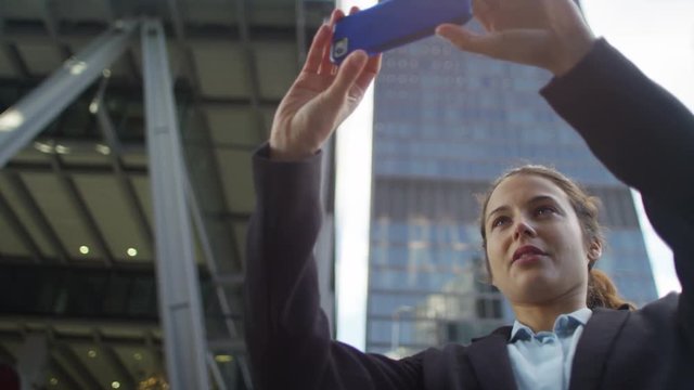  Smiling businesswoman taking a selfie with smartphone outdoors in city
