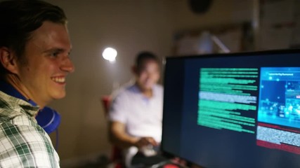 Young men working in front of computers with headphones on - Powered by Adobe