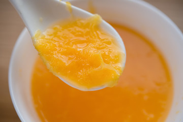Fototapeta na wymiar spoon taking out fresh orange juice with a full filled bowl on background