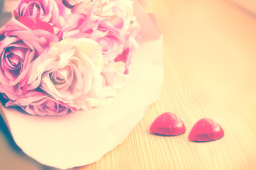 Bouquet of pink and white rose and two red hearts on a wooden background
