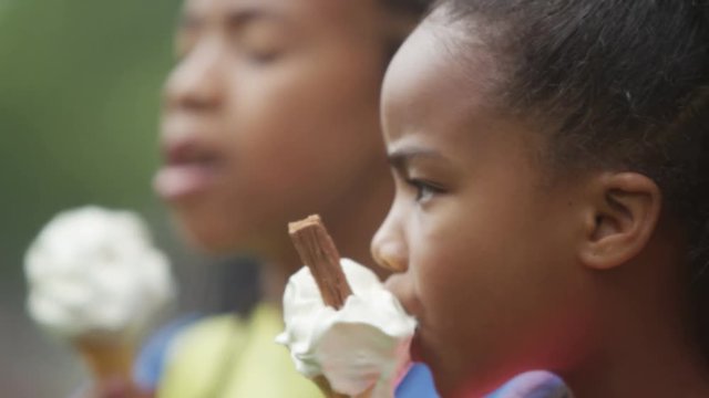  Portrait of African American brother & sister enjoying ice creams in the park. 