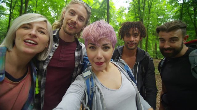  Group of friends hiking in the woods pose to take a selfie. 