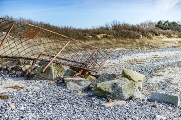 alter zerstörter Grenzzaun am Strand vor blauem Wasser, Absperrung
