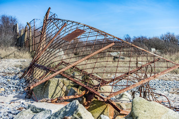 alter zerstörter Grenzzaun am Strand vor blauem Wasser, Absperrung
