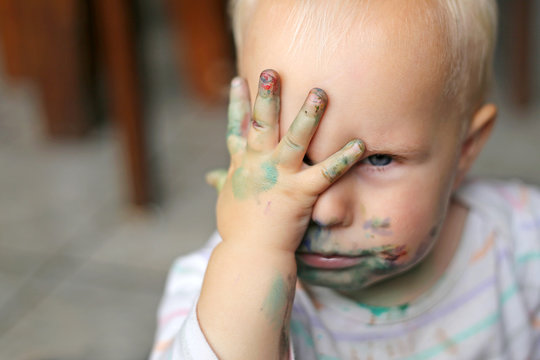 One Year old Baby Girl Covering her messy painted face with her little hand