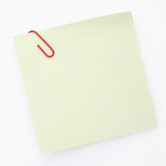 Yellow sticky note with paper clip on the white background