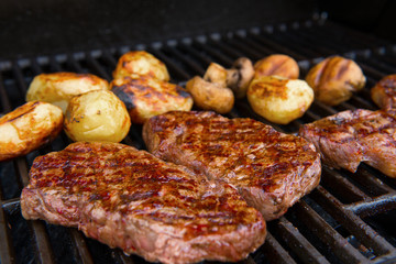 grilled rump steak with mushrooms and potatoes on barbecue