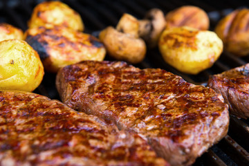 grilled rump steak with mushrooms and potatoes on barbecue