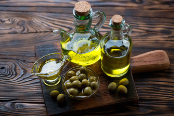 Extra virgin olive oil and olives in a rustic wooden setting