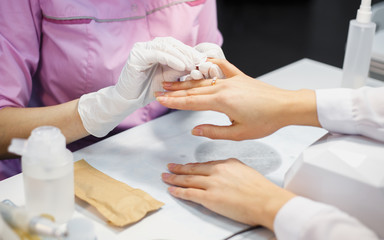 Obraz premium Manicure care procedure, Close-up photo Of Beautician Hand Painting Nails Of Woman In Salon