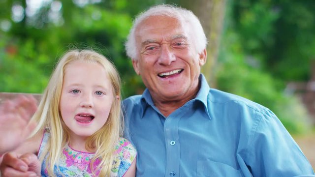  Grandfather & granddaughter make a video call in the garden