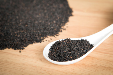 spoon of black sesame in front of a blurry pile of black sesame.