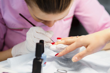 Manicure care procedure, Close-up photo Of Beautician Hand Painting Nails Of Woman In Salon